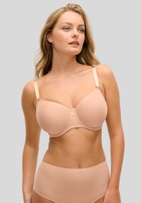 Vaaleanpunainen muotoiltu rintaliivit, joissa sileä kangas, toppituki, säädettävät olkaimet ja koristeellinen pitsikoriste kuppien alla.