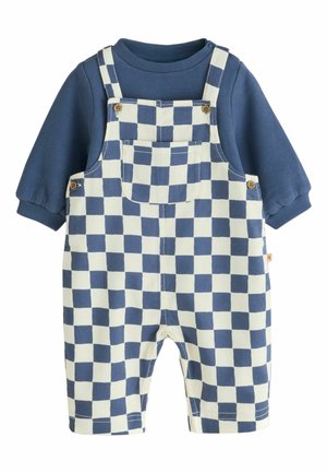 Chemise bleue à manches longues sous une salopette à carreaux bleus et blancs avec poche avant et boutons en bois.