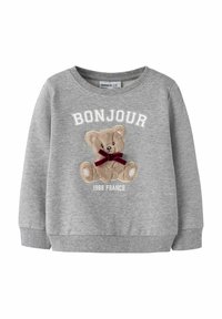 Šedá mikina s dlouhými rukávy, na které je vyšitá grafika medvěda, červená mašle a text "BONJOUR 1988 FRANCE" v bílé barvě.