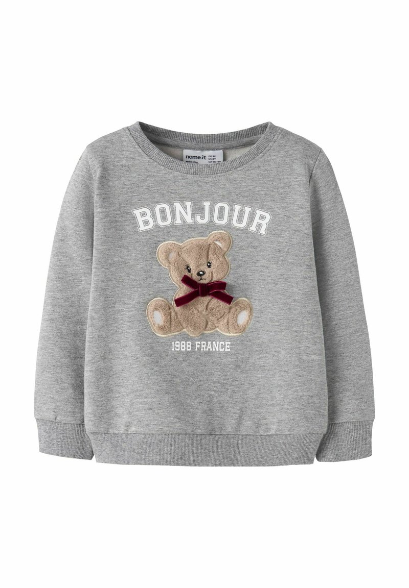 Šedá mikina s dlouhými rukávy, na které je vyšitá grafika medvěda, červená mašle a text "BONJOUR 1988 FRANCE" v bílé barvě.