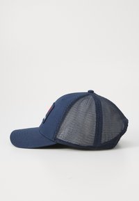 Cappellino blu navy con un pannello frontale solido e retro in rete. Presenta una visiera curva e una toppa rettangolare con logo sul lato.