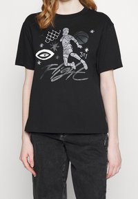 Black cotton t-shirt featuring a printed basketball player graphic, stars, a spiderweb, and the text “Flight” in silver and white.