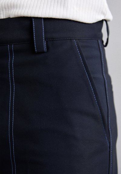 Navy blue trousers featuring contrasting light blue stitching, smooth texture, and a fitted waistband with belt loops.