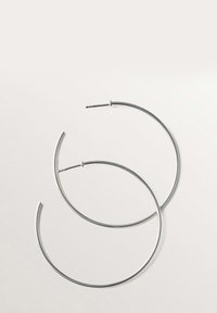 Pendientes de aro de plata con un diseño circular y sencillo. Acabado de metal suave, con una estructura de alambre delgado y un cierre de perno.