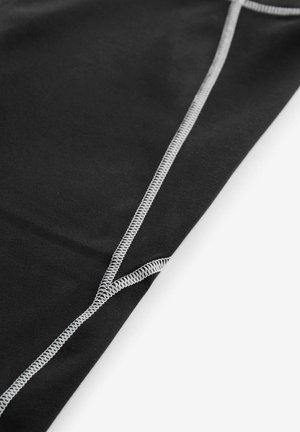 Sort stof med en glat tekstur, der har kontrasterende grå syninger langs sømme og en foldet kant for detaljering.