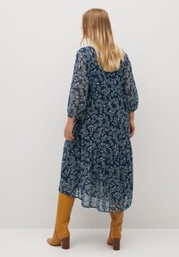 Námořnická modrá květinová midi šaty s průhlednými dlouhými rukávy a podšívkovou sukní. Nosí se s kozačkami do kolen v karamelové barvě.