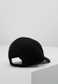 Schwarze Baumwollmütze mit gebogenem Schirm, verstellbarem Riemen und sechs Belüftungsöffnungen auf der Rückseite. Glatte Textur ohne sichtbare Muster.