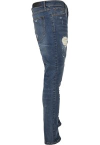 Slim-fit modri kavbojke z obrabljenimi detajli, ki vključujejo raztrgane zaklope in klasičen pet-pocket design. Tekstura je gladka.