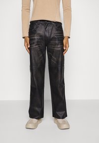 Black faux-leather wide-leg pants with subtle fading and stitching details. Paired with a light long-sleeve top and beige sneakers.