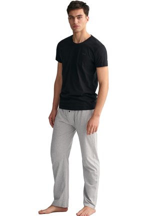 Black cotton t-shirt paired with light grey pajama pants, featuring a relaxed fit and smooth, soft texture. Pants have a button detail.