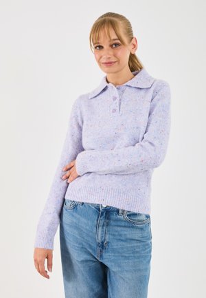 Pull en tricot violet clair avec un col, trois boutons, des poignets côtelés et une texture mouchetée. Porté avec un jean en denim bleu clair.