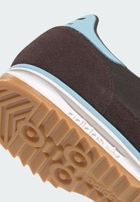 Καφέ σουέντ αθλητικό παπούτσι με τιρκουάζ λεπτομέρεια σε υφασ�μένο επάνω μέρος, διαθέτει λευκή μεσαία σόλα και εξωτερική σόλα από καουτσούκ με ζιγκ-ζαγκ μοτίβο.