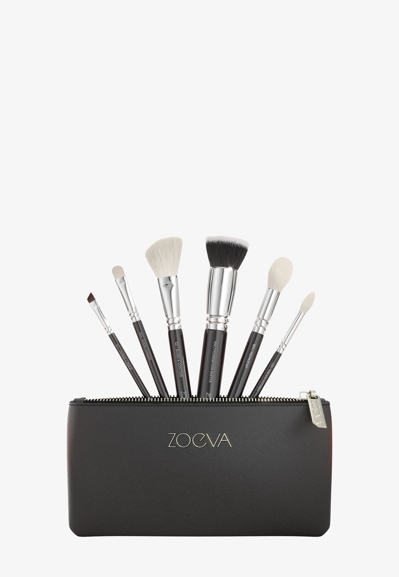 Sechs Make-up-Pinsel mit schwarzen Griffen und silbernen Zwingen in einem teilweise geöffneten schwarzen Reißverschlussetui mit der Aufschrift ZOEVA.