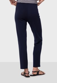 Marina lätta byxor med smal passform, med en jämn textur och elastisk midja. I kombination med svarta platta sandaler.