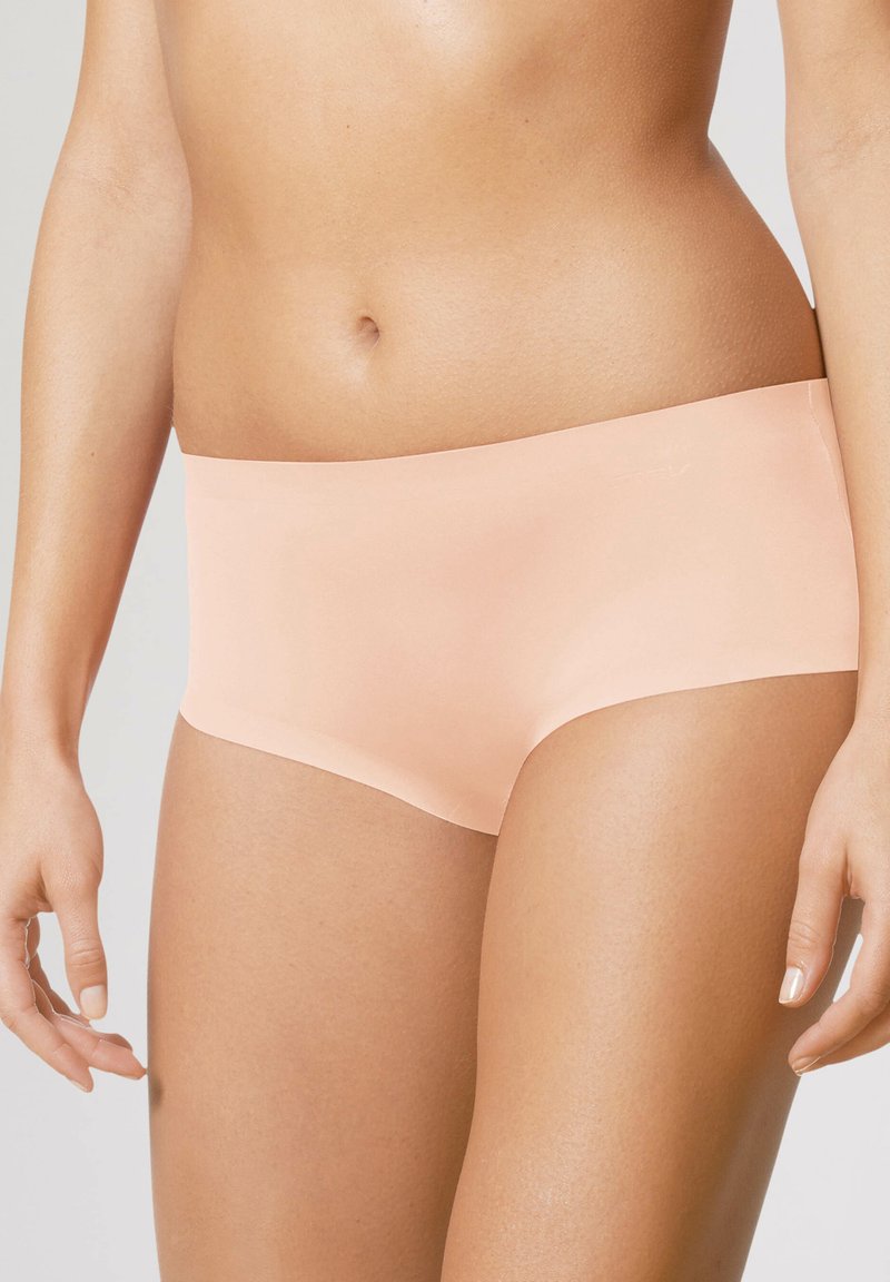 Sous-vêtements hipster de couleur pêche clair, fabriqués à partir d'un matériau doux avec une texture lisse, dotés d'une ceinture élastique et sans coutures visibles.