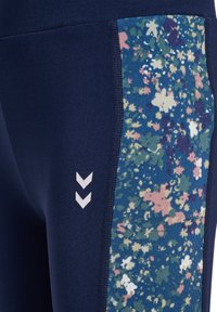 Leggings blu navy con un pannello laterale floreale colorato che presenta accenti in rosa, verde e bianco. Include il logo a zigzag bianco vicino all'anca.
