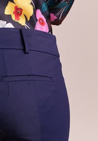 Granatowe spodnie ze szlachetnego materiału, z gładkim przodem, płaskim frontem i pojedynczą tylną kieszenią z subtelnym szwem.