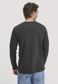 Langärmliges T-Shirt aus dunkelgrauer Baumwolle, mit Rundhalsausschnitt, lockerer Passform und gerippten Bündchen. Die Rückansicht zeigt eine glatte Textur ohne Muster.