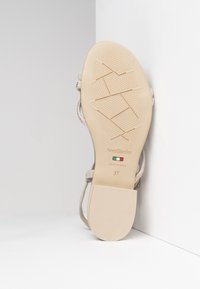 Beige sandal with a smooth rubber sole. Features thin straps and a rectangular heel. "NeroGiardini, Made in Italy, 37" printed inside.