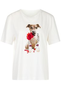 Witte katoenen t-shirt met een afbeelding van een hond die een rode pompon vasthoudt, gekleed in witte sneakers met rode accenten en de tekst "HEART."