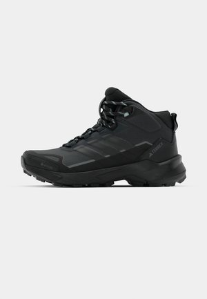 Zwarte wandelboot met een gestructureerde mesh bovenzijde, versterkte neus en een robuuste zool. Voorzien van duurzame veters en GORE-TEX voor waterdichtheid.