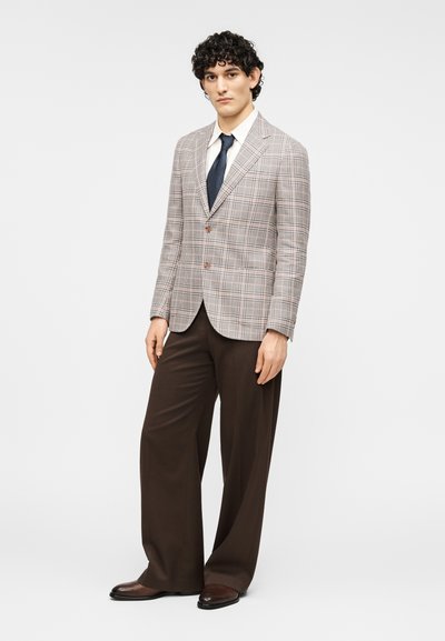 Καρό σακάκι σε ανοιχτούς τόνους με καφέ λεπτομέρειες, συνδυασμένο με σκούρο καφέ παντελόνι. Διαθέτει εφαρμοστή γραμμή και πέτο με εγκοπές.