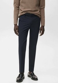 Pantalon ajusté bleu marine en tissu lisse. Doté de passants de ceinture, de poches avant et d'une coupe sur mesure. Associé à des mocassins noirs.