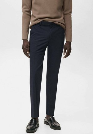 Pantaloni navy slim-fit din material neted. Au brațe pentru curea, buzunare frontale și o croială ajustată. Asociati cu mocasini negri.