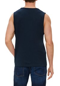 Marineblauses ärmelloses T-Shirt aus Baumwolle, mit rundem Halsausschnitt und lockerer Passform, kombiniert mit dunklen Jeans.