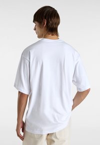 Witte oversized katoenen t-shirt met korte mouwen, ronde hals en een gladde textuur, gezien vanaf de achterkant. Geen patronen of graphics zichtbaar.