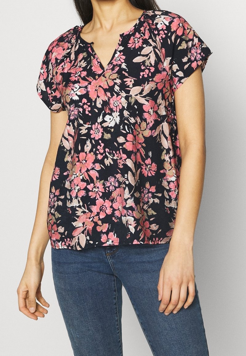Námořnická květinová blůza s krátkými rukávy, zdobená růžovými a bílými květy. Výstřih do V se slabou řasenou detailou a lehký materiál.