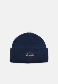 Un bonnet tricoté bleu marine avec une texture côtelée et un revers. Présente une étiquette du logo Columbia avec des graphiques de montagne en rouge et blanc.