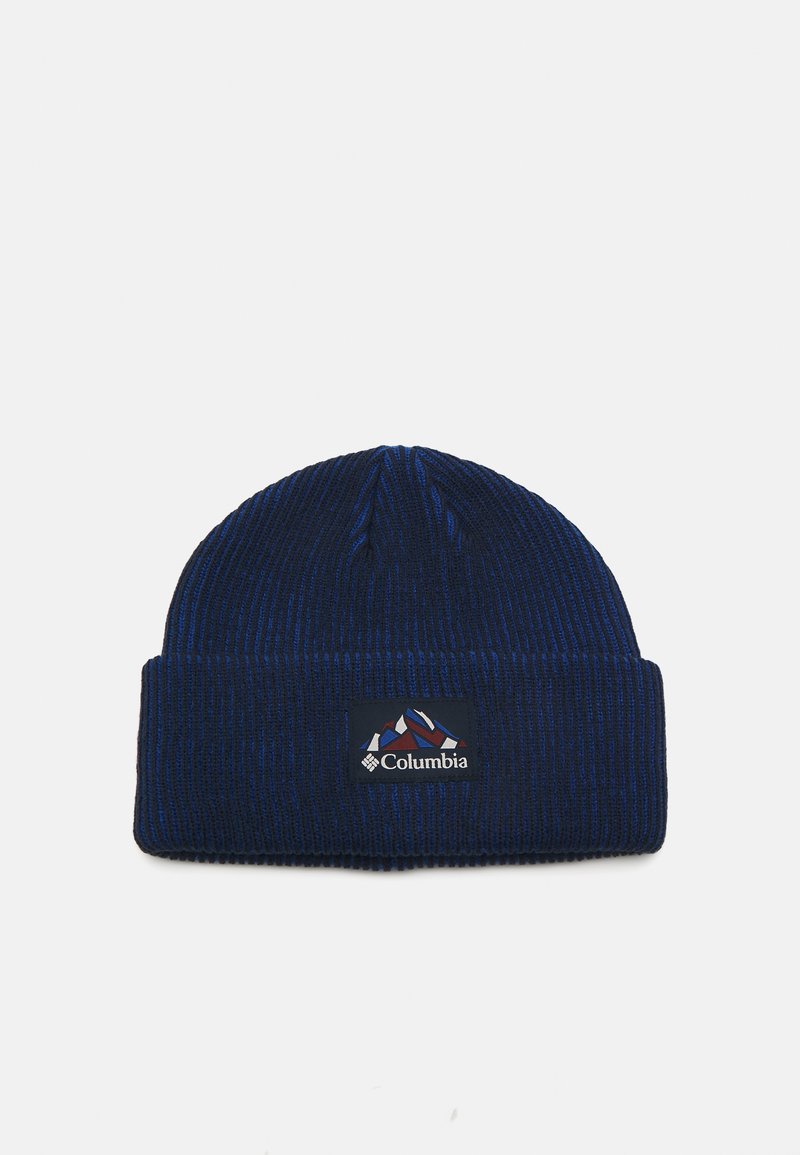 Un bonnet tricoté bleu marine avec une texture côtelée et un revers. Présente une étiquette du logo Columbia avec des graphiques de montagne en rouge et blanc.