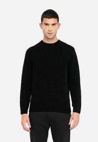 Maglione nero lavorato a maglia con un motivo a griglia testurizzato, scollo rotondo e maniche lunghe. L'orlo e i polsini a coste aggiungono struttura.