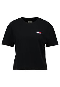 Černé bavlněné tričko s krátkým rukávem, kulatým výstřihem a malou vícobarvou nášivkou na levé hrudi, která obsahuje červené, bílé a modré pruhy.