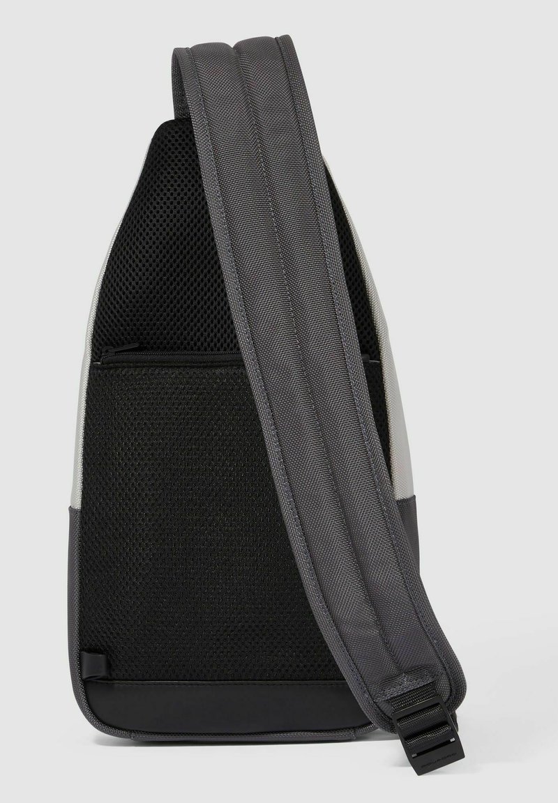 Borsa a tracolla grigia con retro in rete nera testurizzata, tracolla regolabile e tasca con zip. Realizzata in materiale resistente con accenti a contrasto.