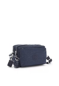 Navy blue nylon crossbody bag with two zippered compartments, rubber logo, and a clipped monkey keychain. Features a woven adjustable strap.