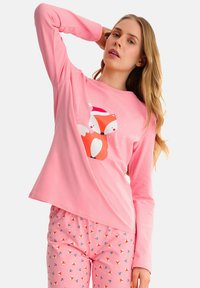 Haut à manches longues rose avec un motif de renard rouge et blanc. Pantalons de pyjama assortis en rose avec un motif de renards et de baies répété. Texture de tissu douce.