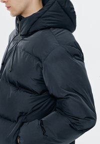 Kurtka puchowa w ciemnym granacie, z pikowanym wzorem, zapięciem na zamek błyskawiczny, kapturem ze sznurkiem oraz elastycznymi mankietami dla zwiększonego ciepła i komfortu.