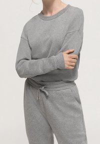 Grå sweatshirt med rund hals, ribbade muddar och avslappnad passform, matchad med grå sweatpants med dragsko i midjan.