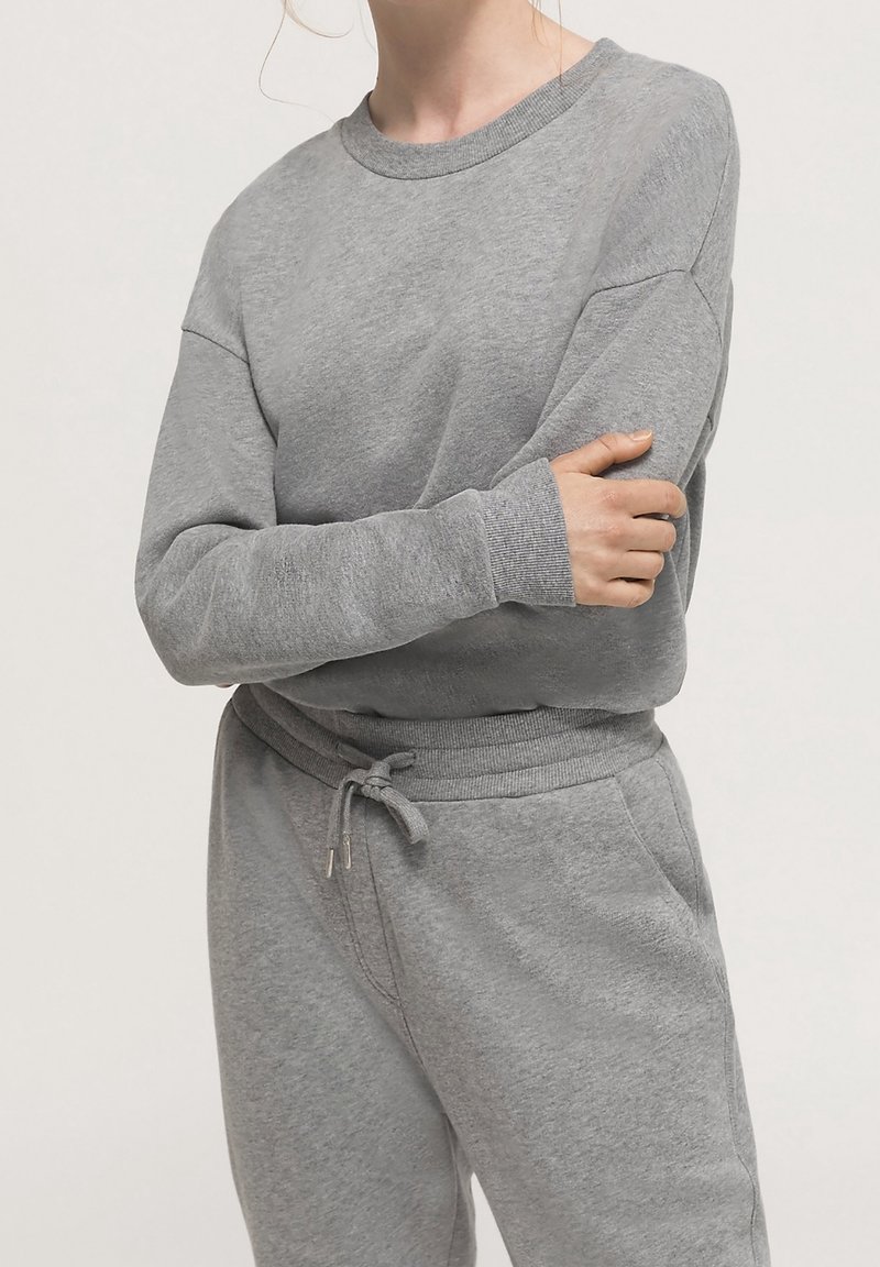 Grå sweatshirt med rund hals, ribbade muddar och avslappnad passform, matchad med grå sweatpants med dragsko i midjan.