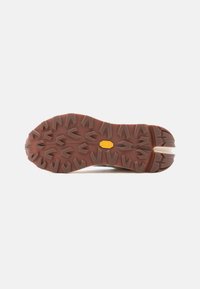 Καφέ λαστιχένια σόλα πεζοπορίας με έντονα μοτίβα πρόσφυσης και κίτρινο λογότυπο Vibram στο κέντρο.