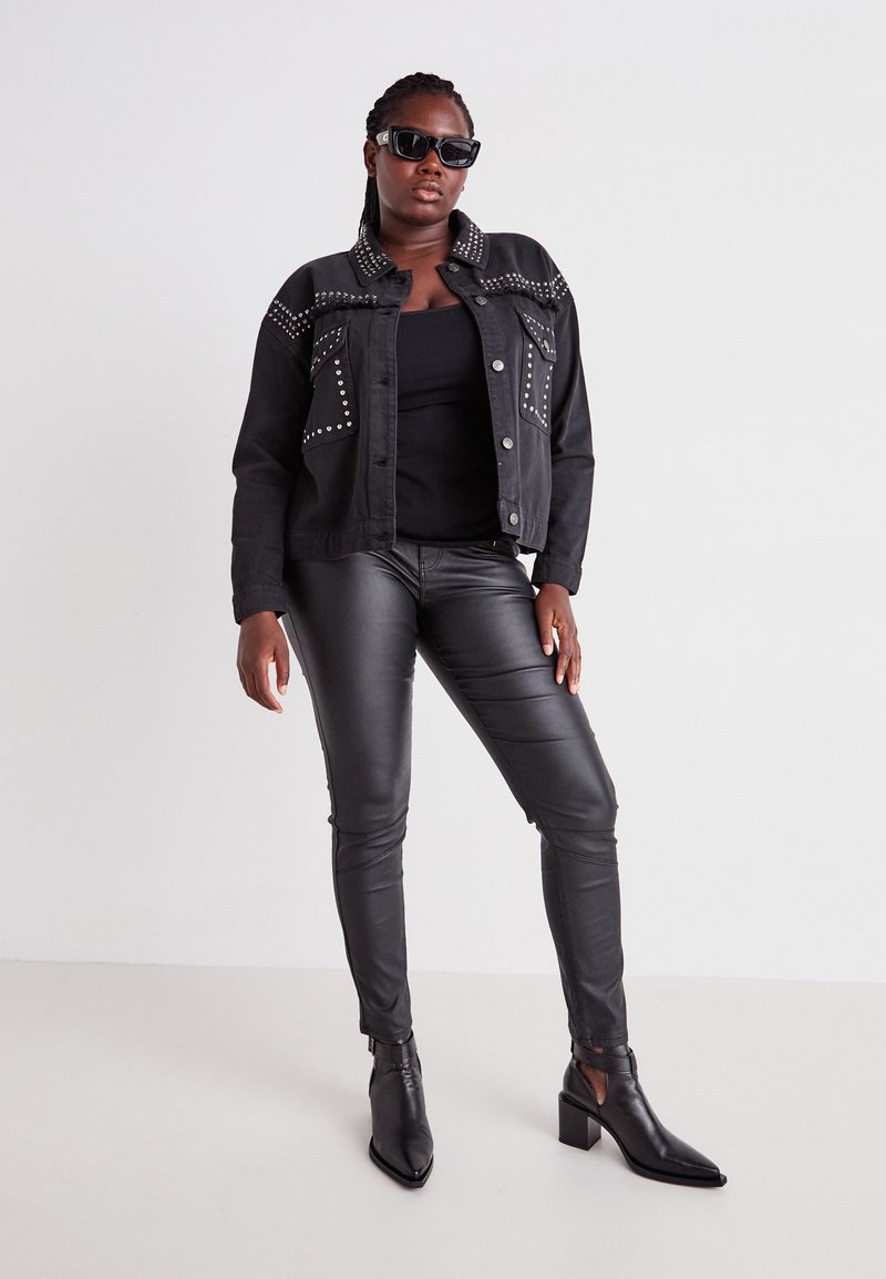 Black denim jacket with studded accents, black tank top, black leather pants, and pointed ankle boots. Sunglasses complete the look.