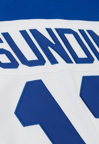 Maglia da hockey bianca con accenti blu. Presenta il nome ricamato "SUNDIN" e il numero "13" in un carattere in grassetto e a blocchi. Tessuto testurizzato.