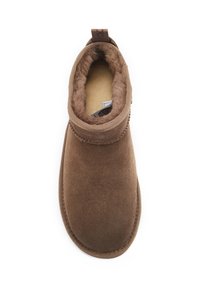 Brązowy zamszowy botek sięgający kostki z miękką, teksturowaną podszewką, okrągłym czubkiem i szytym szwem. Posiada małą pętelkę z tyłu ułatwiającą zakładanie.