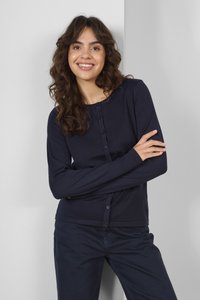 Námořnický cardigan s dlouhým rukávem, kulatým výstřihem, texturovanou tkaninou a předním zapínáním na knoflíky. V kombinaci s odpovídajícími tmavými kalhotami.