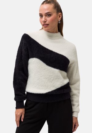 Fuzzy pullover sweater with an asymmetric black and white design, high neck, and ribbed cuffs. Soft texture, modern silhouette, and casual fit.