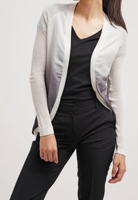 Lehký cardigan ve stupních krémové a šedé barvy, s texturovaným pleteným rukávem a hladkým, jemným předním dílem. Design s otevřeným předním provedením.