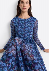 Vestido de manga larga en tejido transparente con un vibrante patrón floral azul y acentos en verde, escote redondo y falda fluida.