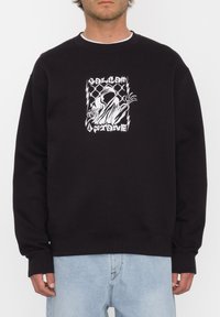 Sudadera negra con un gráfico central en blanco que representa una figura esquelética con una rosa, contra un fondo decorado. Material de algodón.